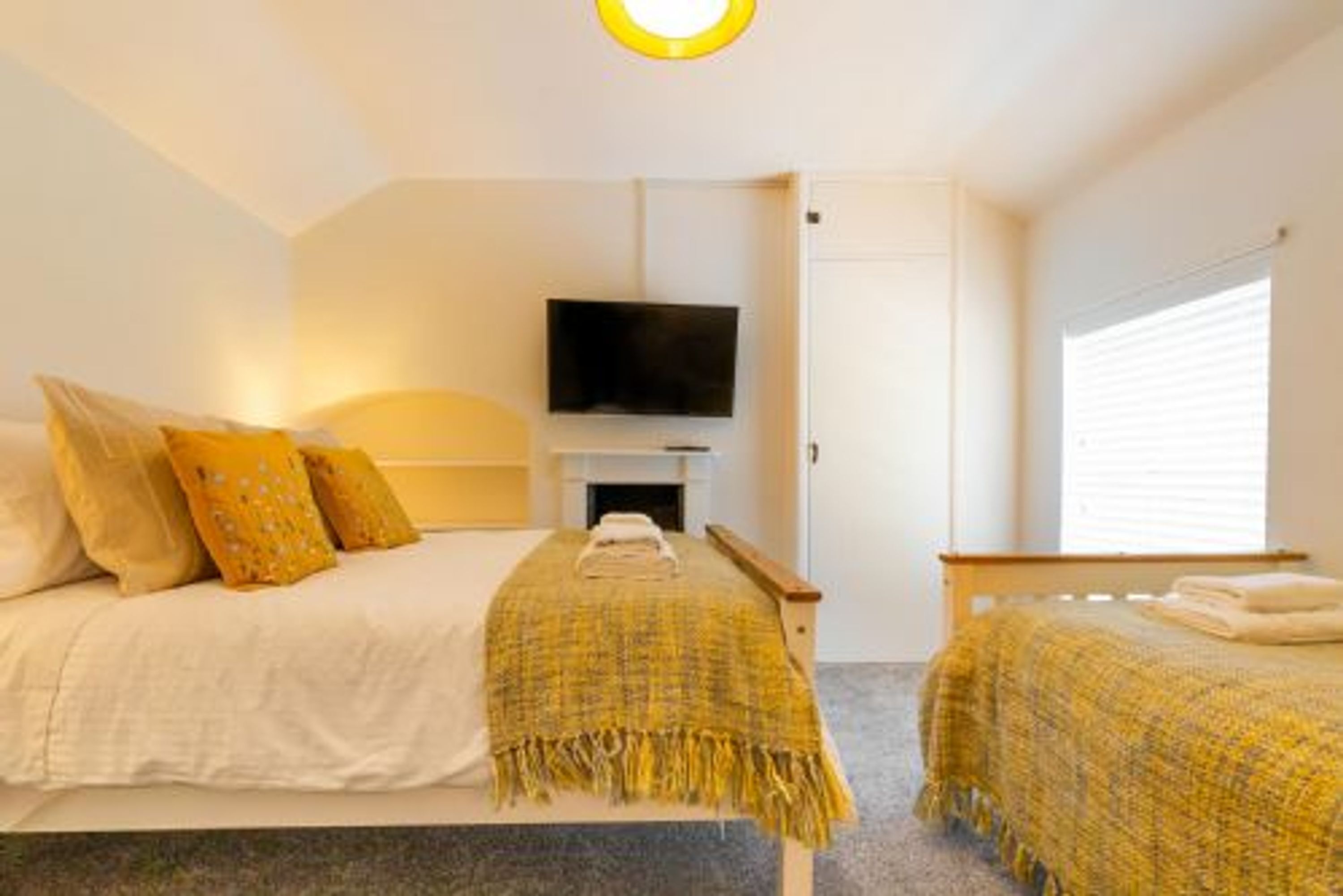 A bedroom with a bed, a TV, and a window.