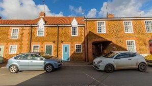 A residential street with two brick houses, one with a blue door and another with a visible garage entrance. - Host Stay The Courtyard (King's Lynn)