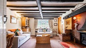 A cozy living room with exposed wooden beams, a fireplace, and a comfortable sofa. - Host Stay Sandpipers (Holt)