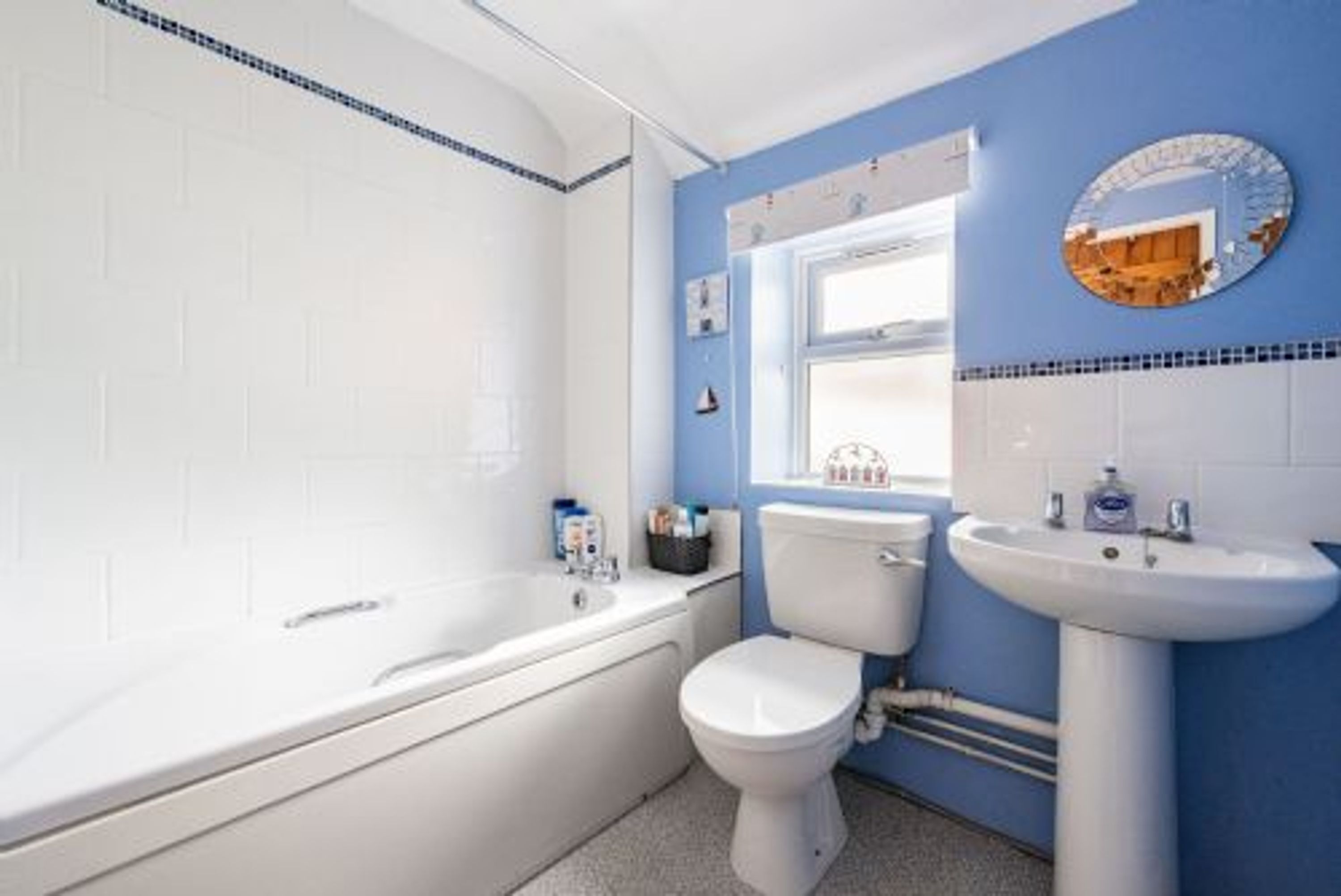 Un bagno con una vasca da bagno bianca, un water bianco e un lavandino bianco.
