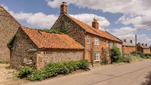 A traditional stone house with a tiled roof, a small front garden, and a clear road in front. - Host Stay Sandpipers (Holt)