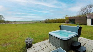 A hot tub in a backyard with a view of the countryside. - Host Stay Willow Barn (Norwich)