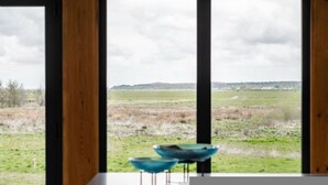 A room with large windows offering a view of a grassy field and distant hills. - Host Stay Willow Barn (Norwich)