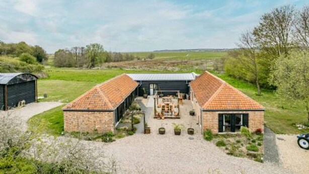 A farmhouse with a central open area, two brick buildings, and a gravel driveway. - Host Stay Willow Barn (Norwich)