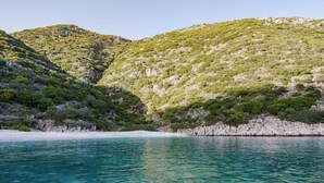 Et kystlandskab med krystalklart turkis vand, klippefremspring og frodig grøn vegetation.