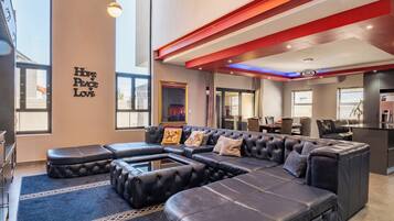 A modern living room with a sectional sofa, ottomans, and a wall with 'Hope Peace Love' text.