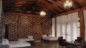 A rustic room with two beds, a wooden wall, a chandelier, and a large window with curtains. - Kuriftu Entoto Adventure Park (Addis Ababa)