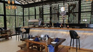 A restaurant with a bar area, wooden tables, and a wine rack in the background. - Kuriftu Entoto Adventure Park (Addis Ababa)