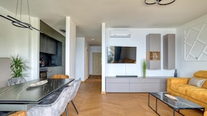 Ein modernes Wohnzimmer mit Essbereich, Küche und einer Couch.