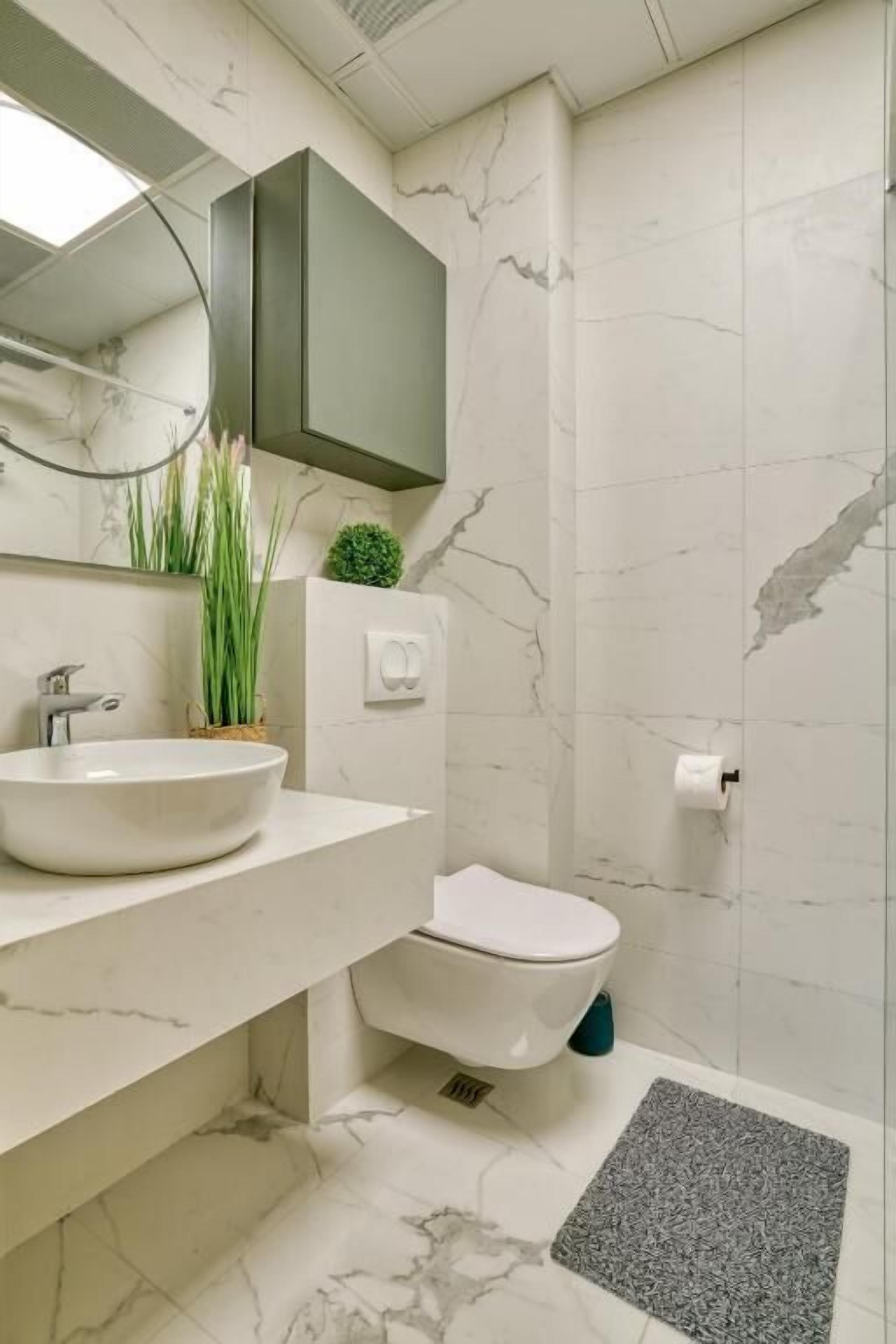 A modern bathroom with a white sink, a toilet, and a shower area.