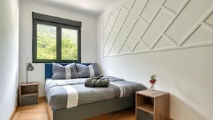 Ein Schlafzimmer mit einem Bett, einem Fenster, einem Nachttisch und einer Wand mit geometrischen Mustern.