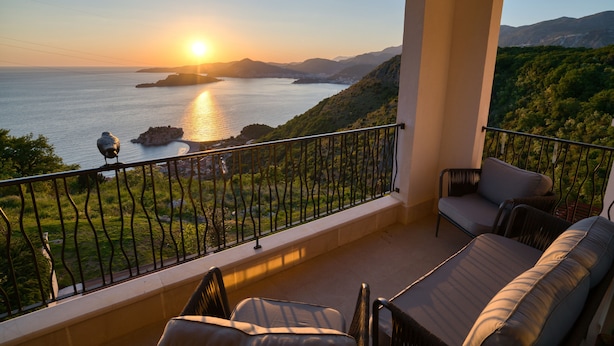 Ein Balkon mit Blick auf das Meer und die Berge bei Sonnenuntergang.