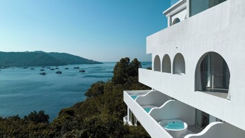Un edificio moderno con piscina, con vistas a una zona costera y barcos.