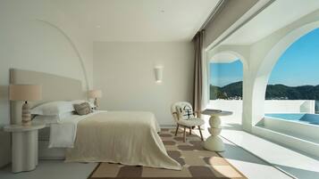 Un dormitorio moderno con una cama grande, una silla, una mesita y vistas a una piscina y montañas.