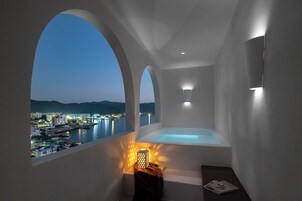 Un baño moderno con bañera, vistas a un paisaje urbano y una lámpara de diseño original.