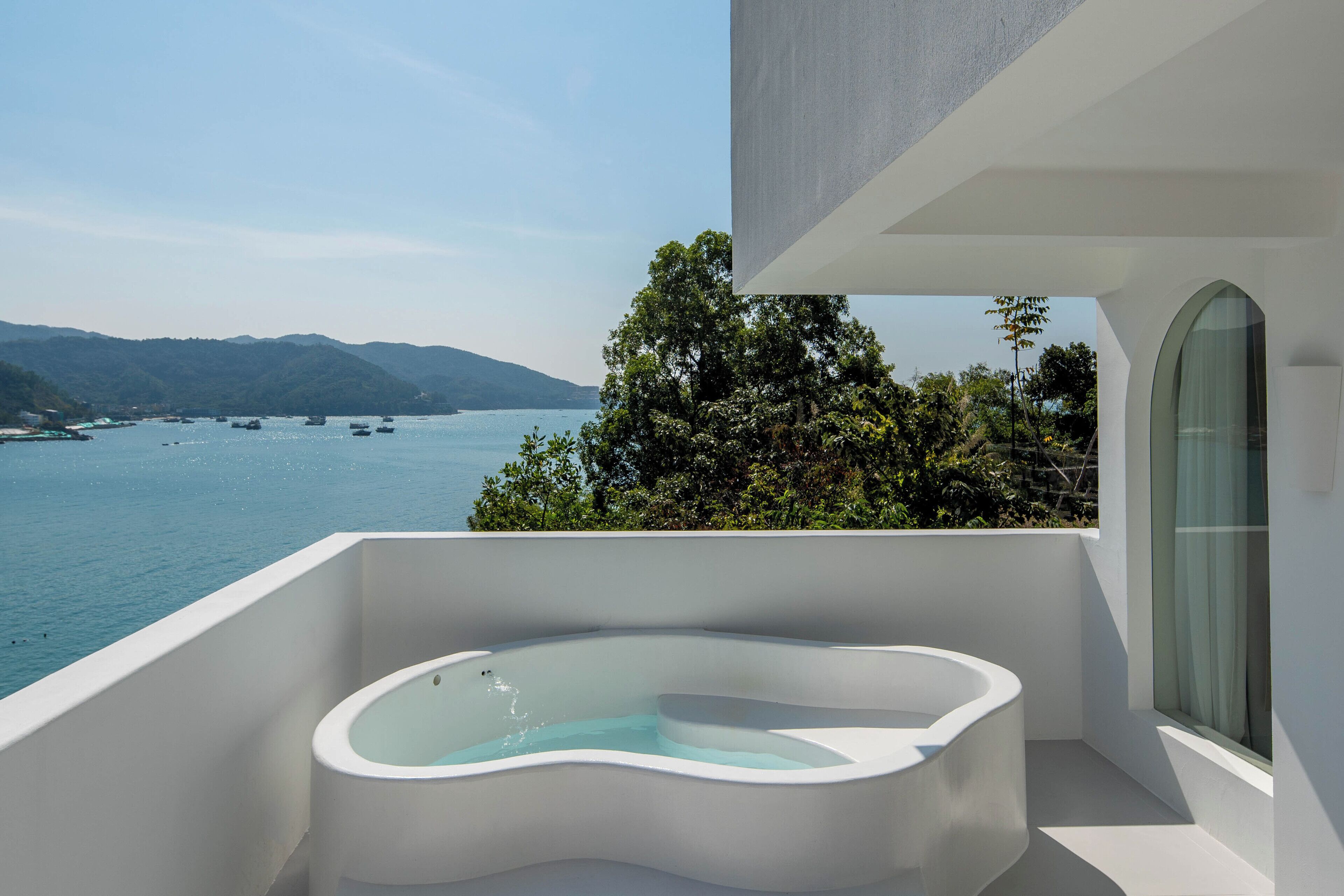 A modern bathroom with a freestanding bathtub overlooking a scenic lake and mountains.