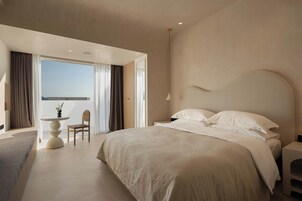 A modern bedroom with a large bed, a small round table, and a chair.