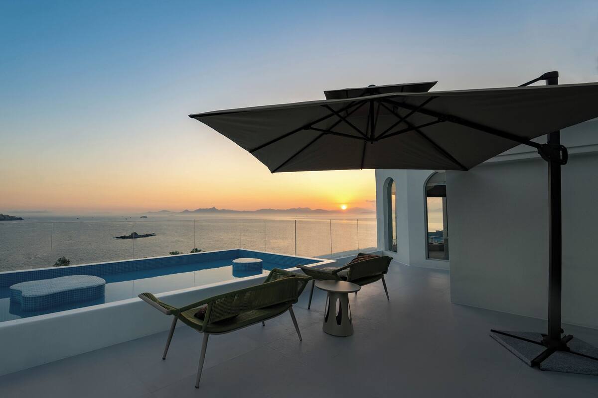 Et rooftop-infinitybassin med havudsigt i solnedgang.