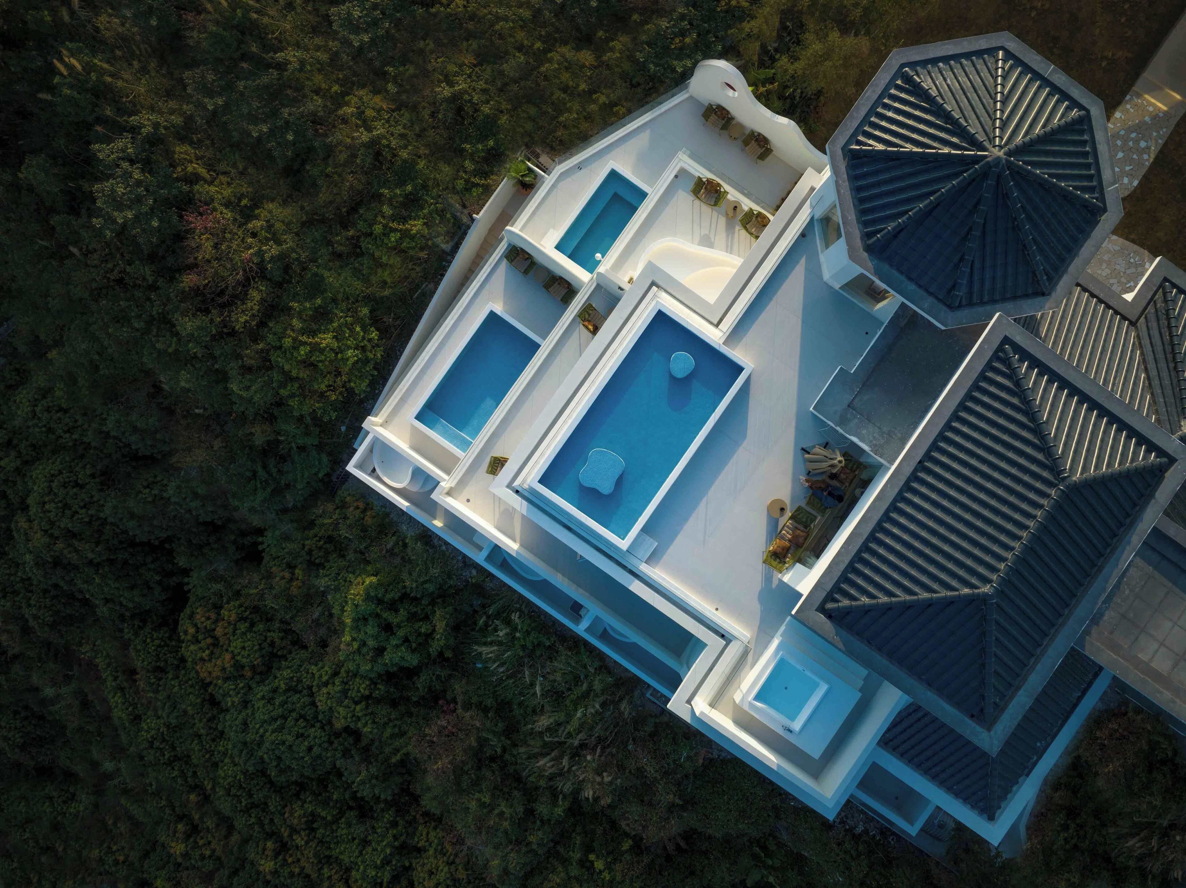 Vista aérea de una casa moderna con una amplia piscina, varias habitaciones y un área exterior cubierta.