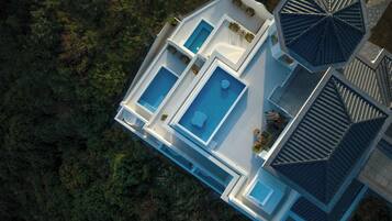 Vista aérea de una casa moderna con una amplia piscina, varias habitaciones y un área exterior cubierta.