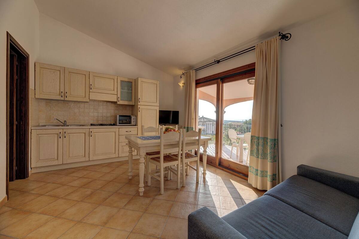 Une cuisine équipée d’armoires, une table à manger et des chaises. Il y a un balcon avec vue.