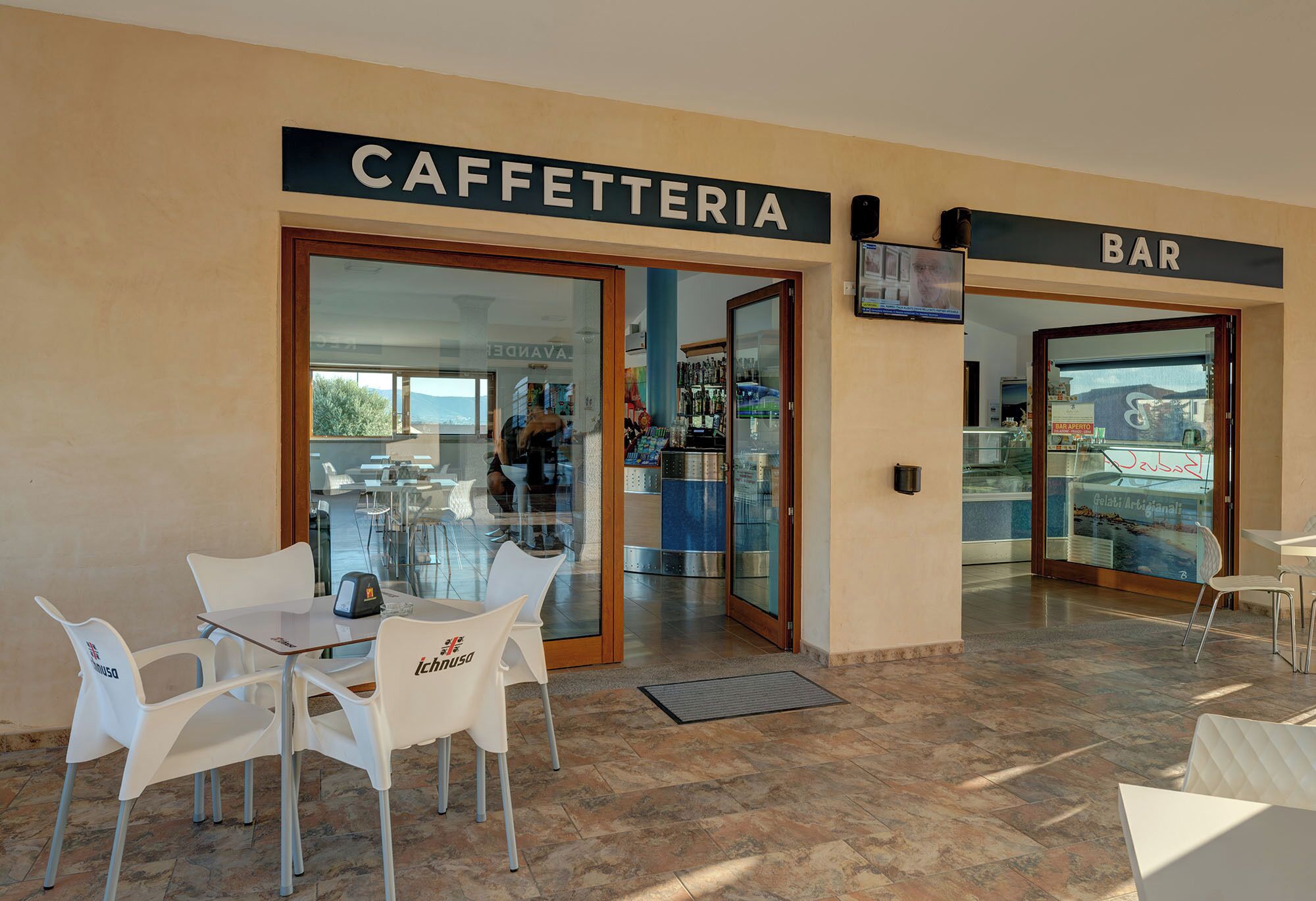 A café and bar with glass doors, white chairs, and a tiled floor.