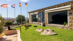 A building with stone walls, a reception sign, and flags. - I Giardini di Badus (Badesi)