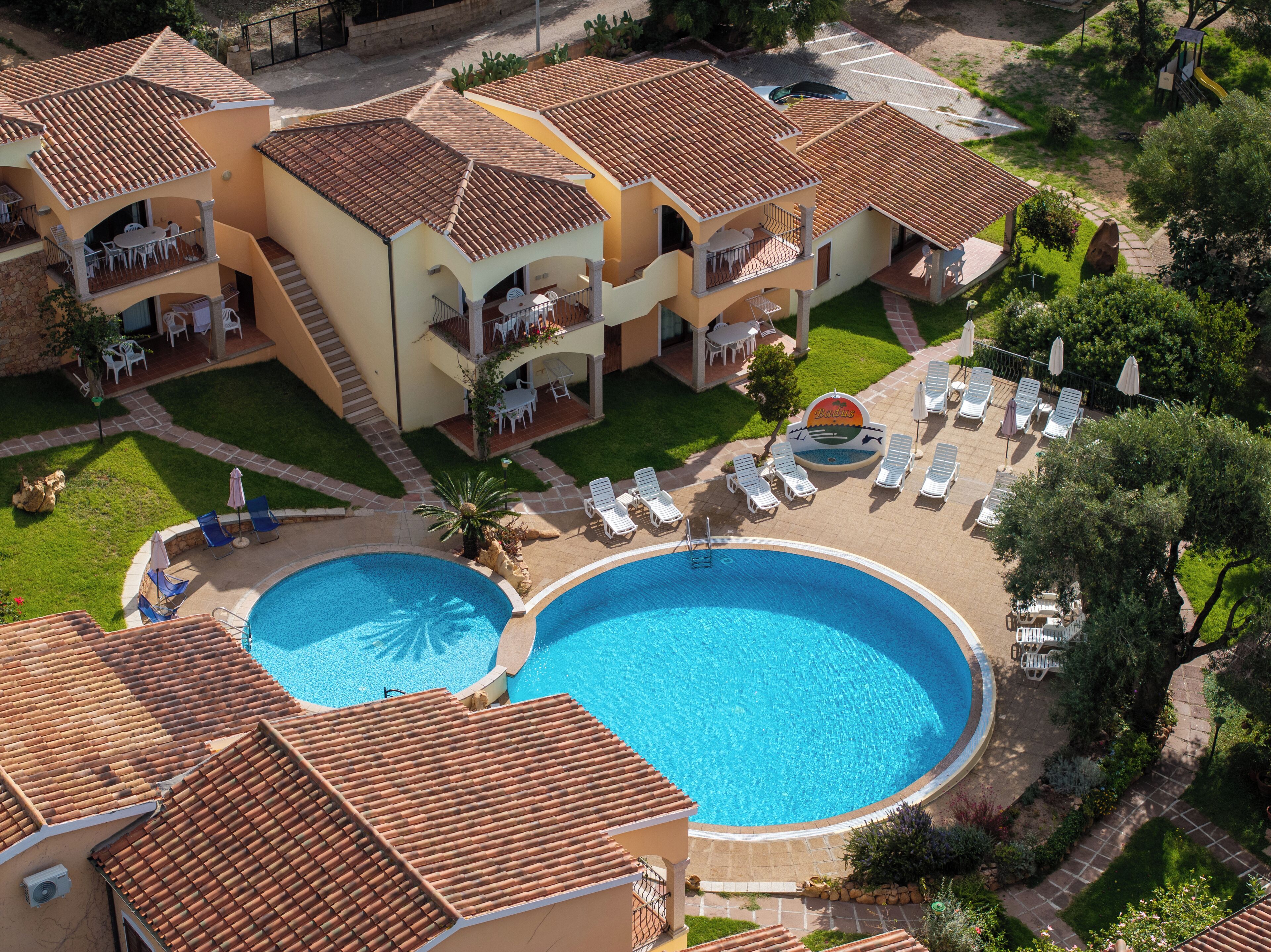 Ein Resort mit zwei Schwimmbecken, mehreren Liegebereichen und einem gepflegten Garten.