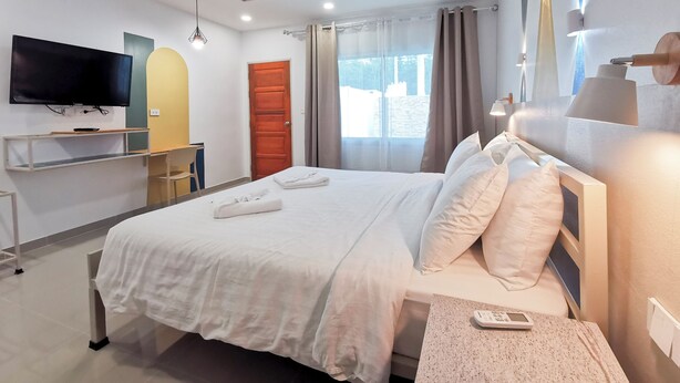 A hotel room with a bed, a TV, a desk, and a window with curtains. - The villa seamlessly blends modern design, refined aesthetics and serene comfort (Muang Pattaya)