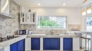 A modern kitchen with a window, built-in microwave, and blue cabinets. - The villa seamlessly blends modern design, refined aesthetics and serene comfort (Muang Pattaya)