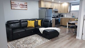 Un apartament modern amb un sofà de pell negra, una taula de dinar i una cuina.
