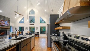 A modern kitchen with a large island, stainless steel appliances, and a fireplace. - Top % Secluded 1.25ac: Spa Bath, Tub & Pull-Thru (Broken Bow)