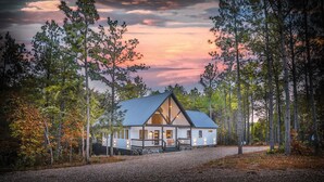 A cabin with a metal roof, surrounded by trees, and a gravel driveway. - Top % Secluded 1.25ac: Spa Bath, Tub & Pull-Thru (Broken Bow)