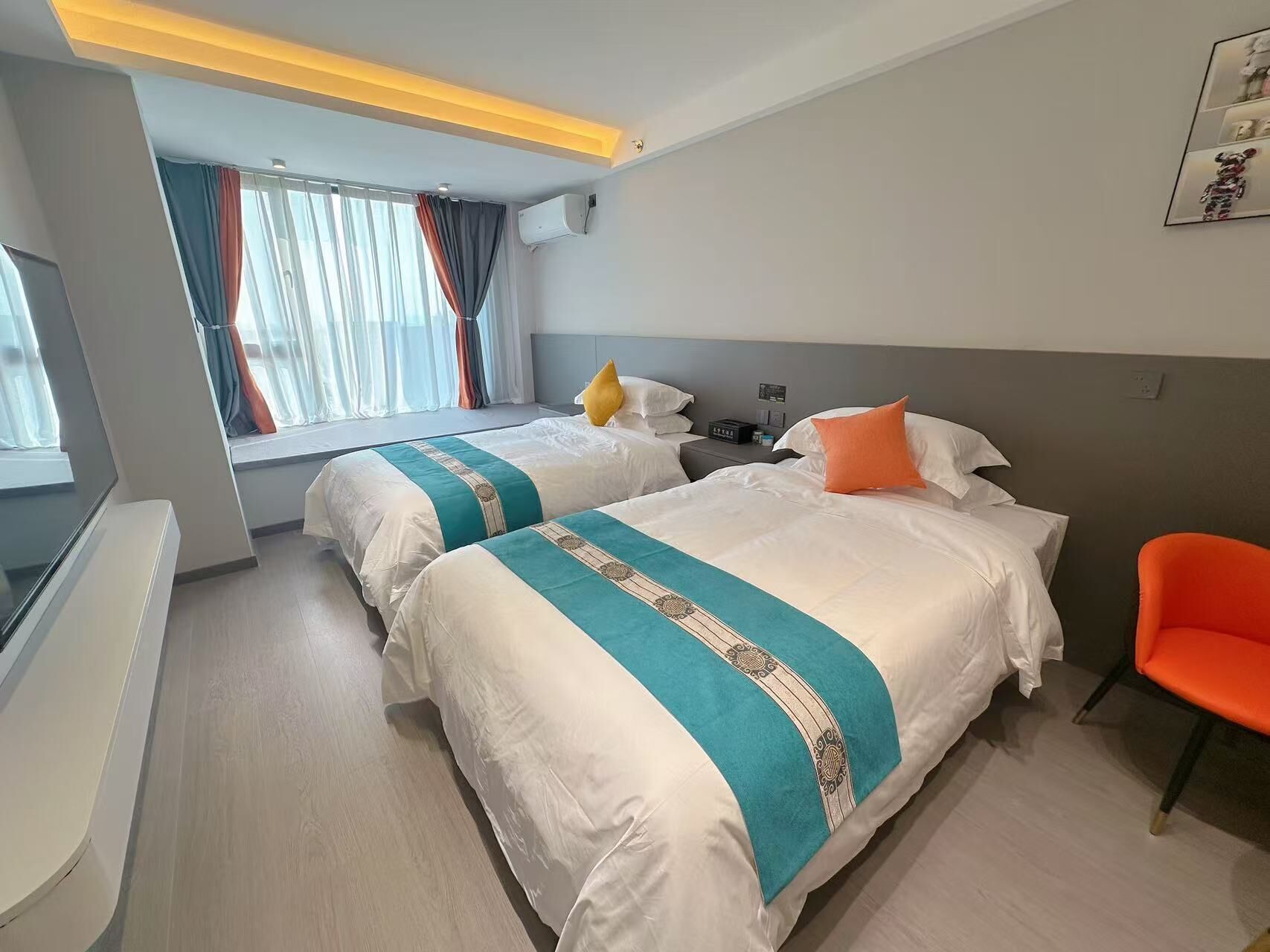 A hotel room with two beds, a desk, and a chair.