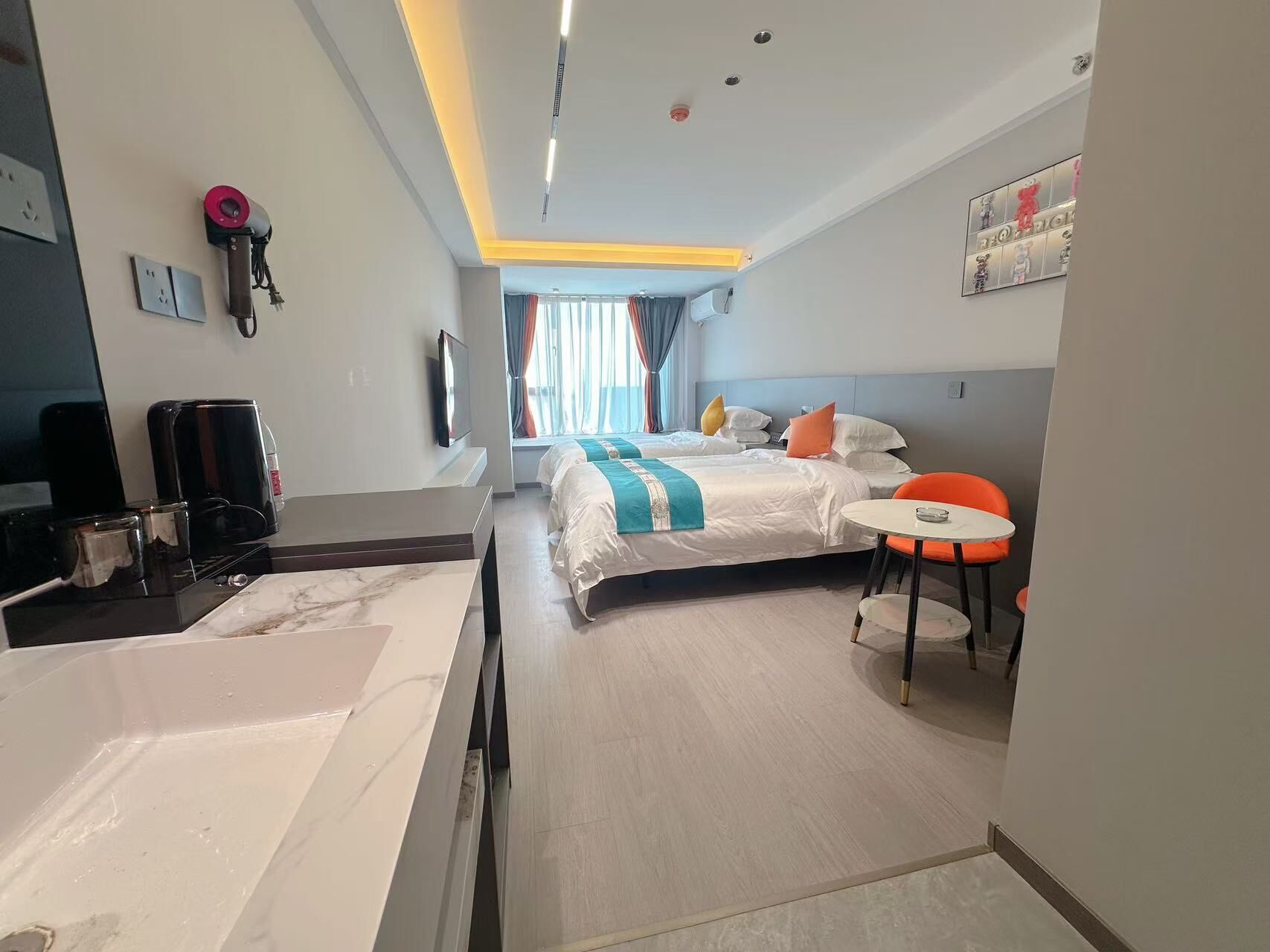 Una habitación de hotel con cama, escritorio con cafetera, una mesita y una silla.