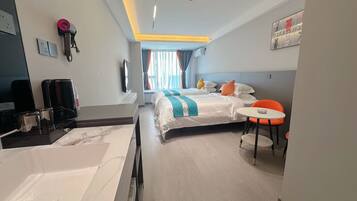 Una habitación de hotel con cama, escritorio con cafetera, una mesita y una silla.