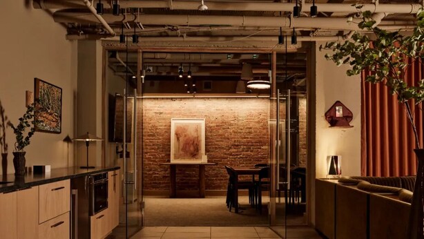 A modern kitchen with a brick wall, wooden cabinets, and a dining area with a table and chairs. - Mint House Washington DC Downtown by Kasa (Washington)