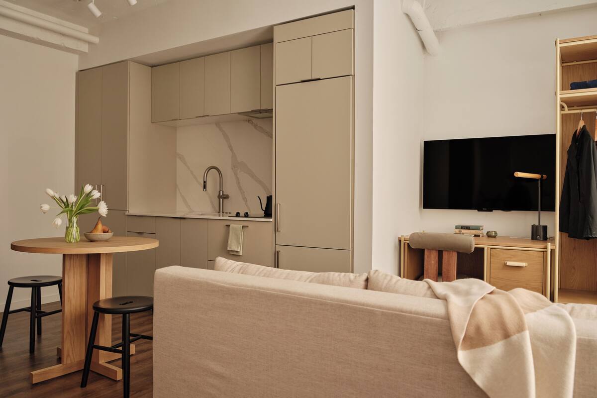 Un espace de vie compact comprenant un coin cuisine, un canapé, une petite table à manger et un téléviseur.