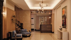 A modern lobby with a wooden staircase, seating area, and a reception desk. - Mint House Washington DC Downtown by Kasa (Washington)