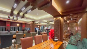 A modern restaurant with wooden tables and chairs, a decorative wall, and a seating area with cushioned benches. - Paradise Premium (Srinagar)