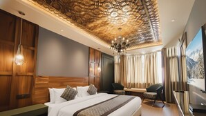 A hotel room with a large bed, wooden paneling, a chandelier, a TV, and a mountain view. - Paradise Premium (Srinagar)