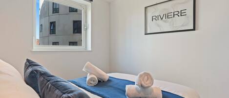 A hotel room with a bed, a window, and a framed sign on the wall.