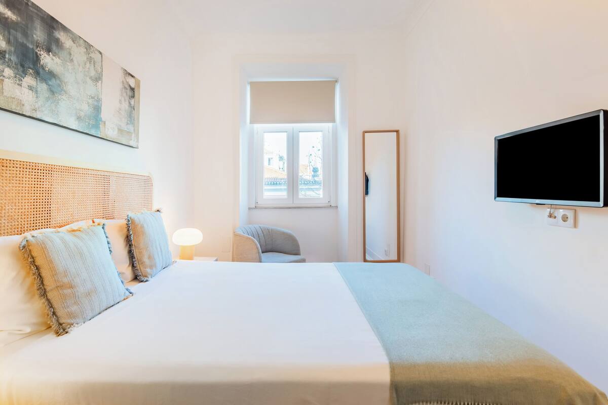 Ein Hotelzimmer mit Bett, großem Fenster, Flachbildfernseher und einem Bild an der Wand.