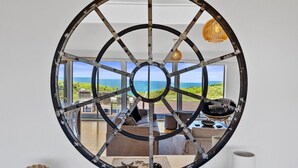 A room with a large circular window overlooking a beach. - Berry's Beach Retreat Ventnor Phillip Island (Ventnor)