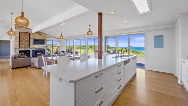 A modern kitchen with a large island, a dining area with a view, and a cozy living room with a fireplace. - Berry's Beach Retreat Ventnor Phillip Island (Ventnor)