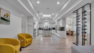Une cuisine moderne avec des meubles blancs, un îlot central et un coin repas doté de chaises jaunes.