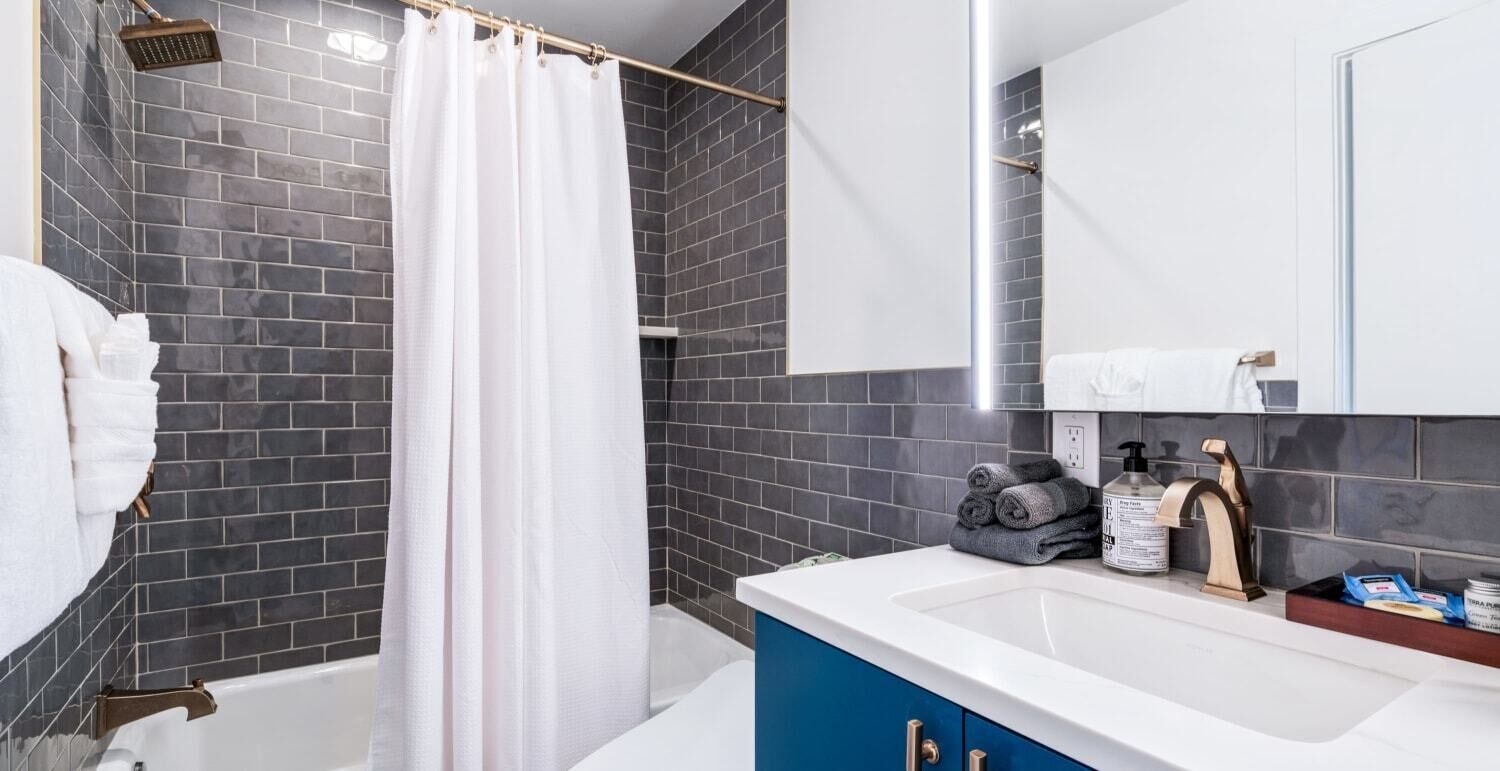 A modern bathroom with a bathtub, shower, and a vanity with toiletries.