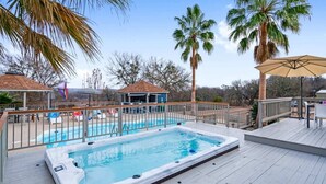 Ein Swimmingpool mit Whirlpool, umgeben von Palmen und einer Terrasse mit Sitzgelegenheiten.