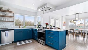 Eine moderne Küche mit blauen Schränken, einer zentralen Kochinsel und einem Essbereich mit Holzkästen.