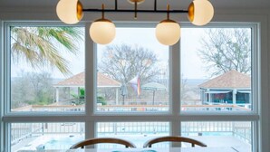 Ein Zimmer mit großem Fenster und Blick auf einen Pool und ein Gartenpavillon.
